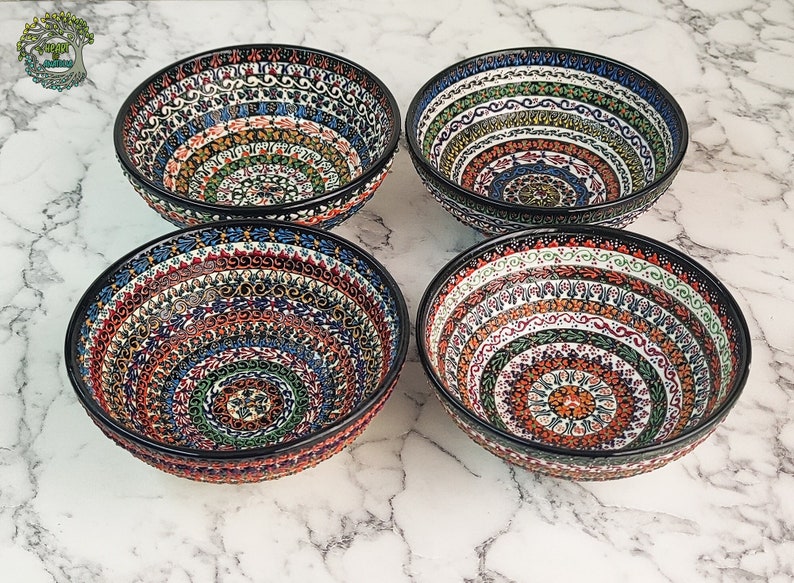 May include: Four ceramic bowls with intricate, colorful patterns. Each bowl features a black rim and a detailed design of concentric circles in shades of red, blue, green, and orange. The bowls are likely for serving food.