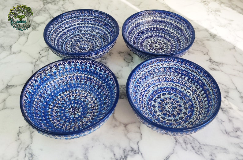 May include: Four blue ceramic bowls with intricate white and blue floral patterns. The bowls are arranged in a square, showcasing their detailed designs. The bowls are likely for serving food.