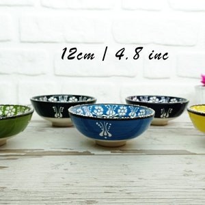 Puede incluir: Una colecci&oacute;n de cinco cuencos de cer&aacute;mica, cada uno de 12 cm de di&aacute;metro, con base blanca y dise&ntilde;os coloridos. Los cuencos son verdes, negros, azules y amarillos, con motivos florales. El texto "12cm / 4.8 inc" es visible.