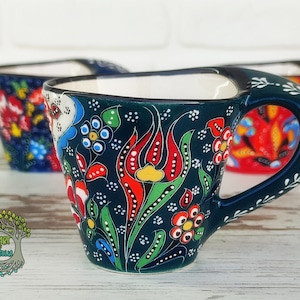 May include: A set of three Turkish coffee cups with floral designs. The cups are made of ceramic and have a dark blue background with colorful flowers and leaves. The cups have a handle on the side and are perfect for serving Turkish coffee.