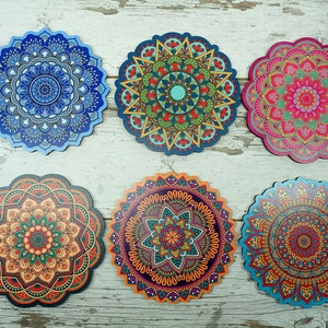 May include: Six decorative coasters with mandala designs. Each coaster features a unique, colorful pattern, including shades of blue, green, red, orange, and pink. The coasters are round with a scalloped edge, perfect for adding a touch of bohemian style to any home.