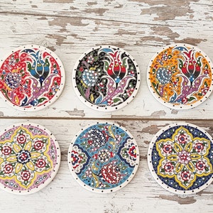 May include: Six round ceramic coasters featuring colourful floral patterns. The coasters have intricate designs with a variety of colours, including red, blue, yellow, green, and white. The coasters are ideal for adding a touch of Turkish art to your home decor.