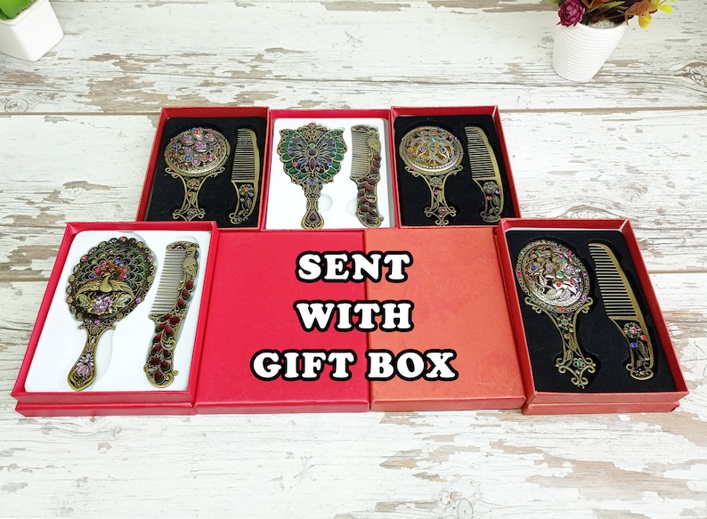May include: Ornate antique-style mirror and comb sets in red gift boxes. The mirrors and combs have intricate designs with colorful jewel accents. The text "SENT WITH GIFT BOX" is displayed.