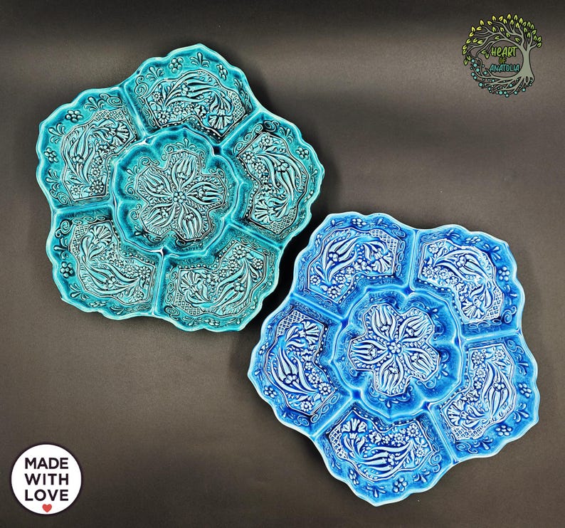 May include: Two ceramic serving platters in shades of blue. The platters have a floral design with a central flower and surrounding compartments. The platters are decorated with white floral patterns. The text "MADE WITH LOVE" is visible.