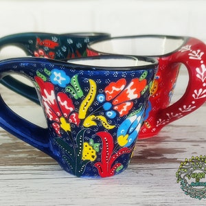 May include: Two Turkish coffee cups with floral designs. The cups are blue and red with colorful floral patterns. The cups are made of ceramic and have a traditional design.