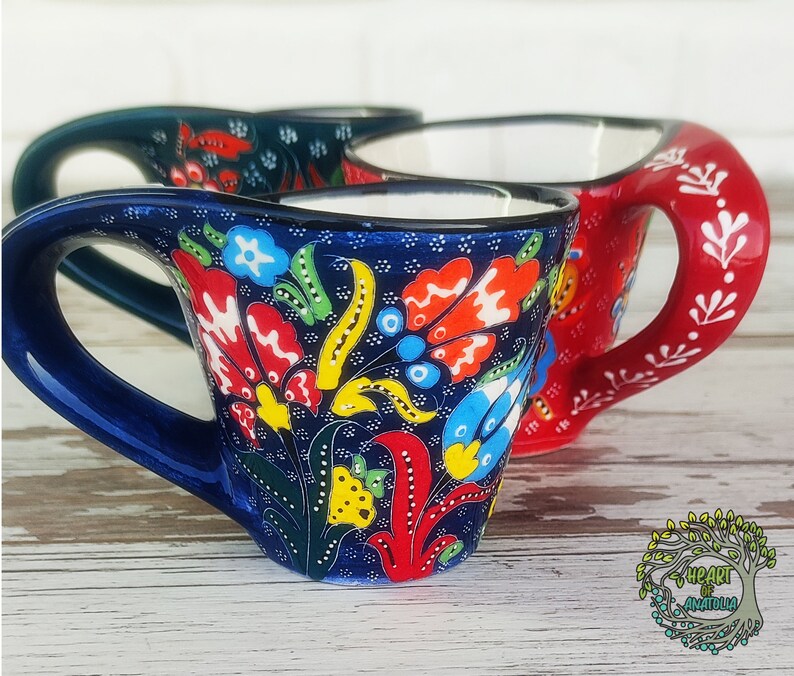 May include: Two Turkish coffee cups with floral designs. The cups are blue and red with colorful floral patterns. The cups are made of ceramic and have a traditional design.