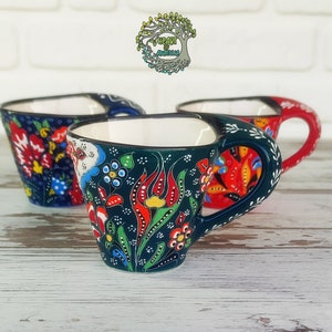 May include: Three Turkish coffee cups with colorful floral patterns. The cups are made of ceramic and have a traditional design. The cups are blue, red, and green.
