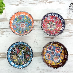 Puede incluir: Cuatro cuencos peque&ntilde;os y redondos de cer&aacute;mica con intrincados y coloridos dise&ntilde;os florales. Cada cuenco presenta una combinaci&oacute;n de colores diferente: naranja, rojo, negro y marr&oacute;n. Los cuencos son probablemente hechos a mano y muestran un dise&ntilde;o tradicional.