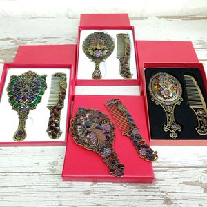 May include: Ornate antique-style mirror and comb sets in red gift boxes. The sets feature detailed metalwork with colorful jewel accents. The mirrors and combs have a peacock or floral design.