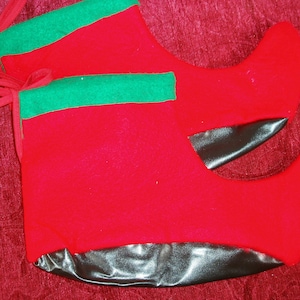 May include: A pair of red felt elf boots with green trim and black soles. The boots have red ties at the top, designed for festive holiday decor.