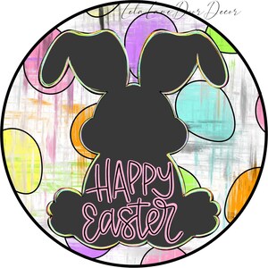 Pu&ograve; includere: Uno sfondo rotondo bianco con una silhouette nera di un coniglio. Il coniglio &egrave; seduto di spalle allo spettatore e ha le parole "Buona Pasqua" scritte in rosa sulla schiena. Lo sfondo &egrave; decorato con uova astratte colorate.