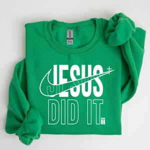 A green sweatshirt with the text "JESUS DID IT" printed on it.