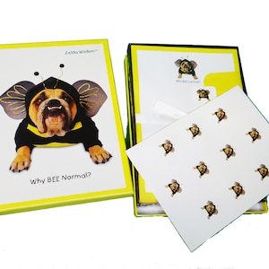 May include: A box of stationery featuring a bulldog dressed as a bee. The box is yellow with green trim and the text "Zelda Wisdom" and "Why BEE Normal?" The stationery inside the box features a white background with a repeating pattern of the bulldog dressed as a bee.