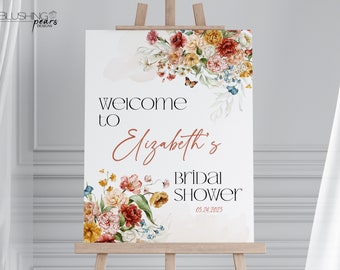 May include: A white welcome sign with a floral design in shades of red, orange, yellow, and blue. The text reads "Welcome to Elizabeth's Bridal Shower 05.24.2023".