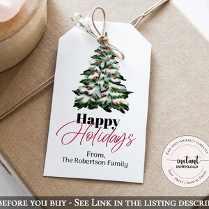 May include: A white gift tag with a watercolor Christmas tree design, red berries, and the text "Happy Holidays." The tag is tied with twine and rests on a wrapped gift. The text "From, The Robertson Family" is also included.