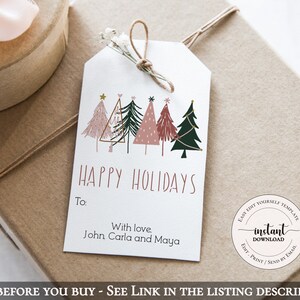 May include: A white gift tag with a string and floral accents, featuring a row of illustrated Christmas trees in pink, green, and gold. The tag reads "HAPPY HOLIDAYS" and includes a personalized message.