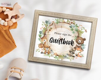 May include: A printable sign with a woodland theme featuring a tree stump with a wreath of leaves and animals. The text on the sign reads "Please sign the Guestbook".