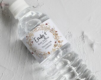 Può includere: Una bottiglia d'acqua in plastica trasparente con un'etichetta bianca. L'etichetta presenta un motivo floreale con fiori secchi e il testo "Emily's Baby Shower 04.10.2022 Thanks for coming!"