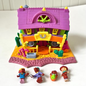 Op de afbeelding: Een kleurrijke miniatuur speelset met een paars dak, oranje accenten en een geel bord. De set bevat kleine figuren van mensen en dieren. De basis is een bruine kleur met een baksteenachtige rand. Een leuk speelgoed voor kinderen.