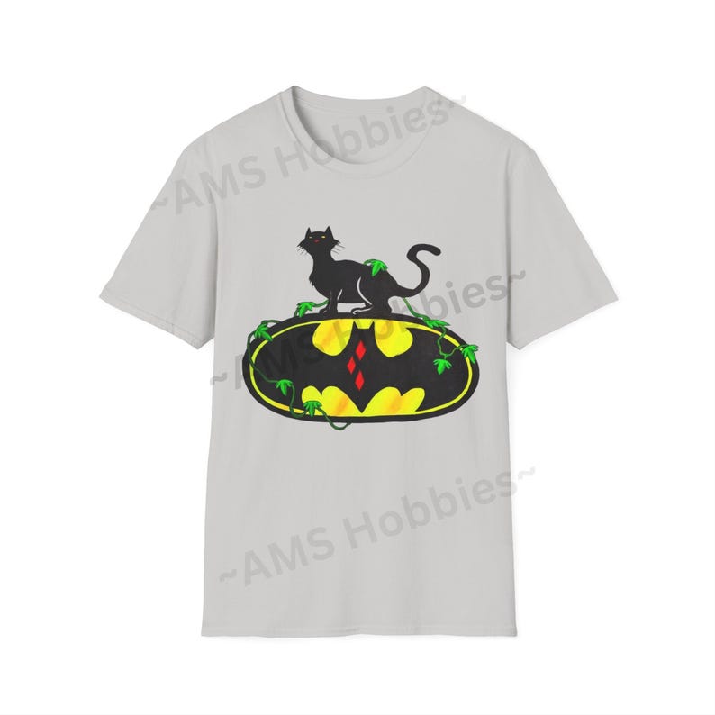 May include: A gray t-shirt with a black cat sitting on top of a yellow and black Batman logo with green vines. The logo has a red diamond in the center.