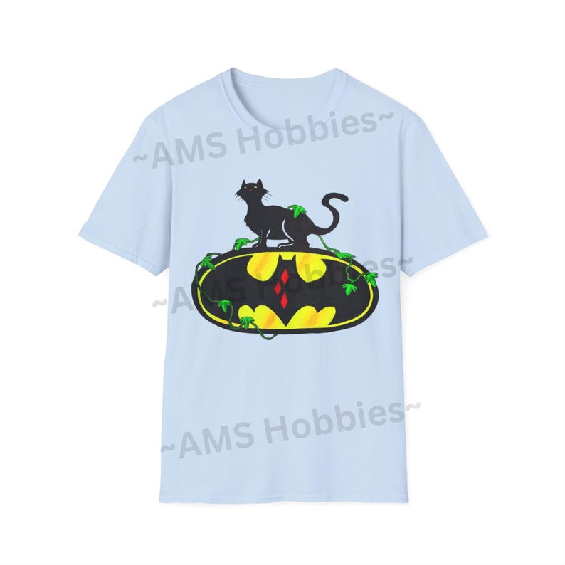 May include: Light blue t-shirt with a black cat sitting on top of a yellow Batman logo with green vines. The text "AMS Hobbies" is printed on the shirt.