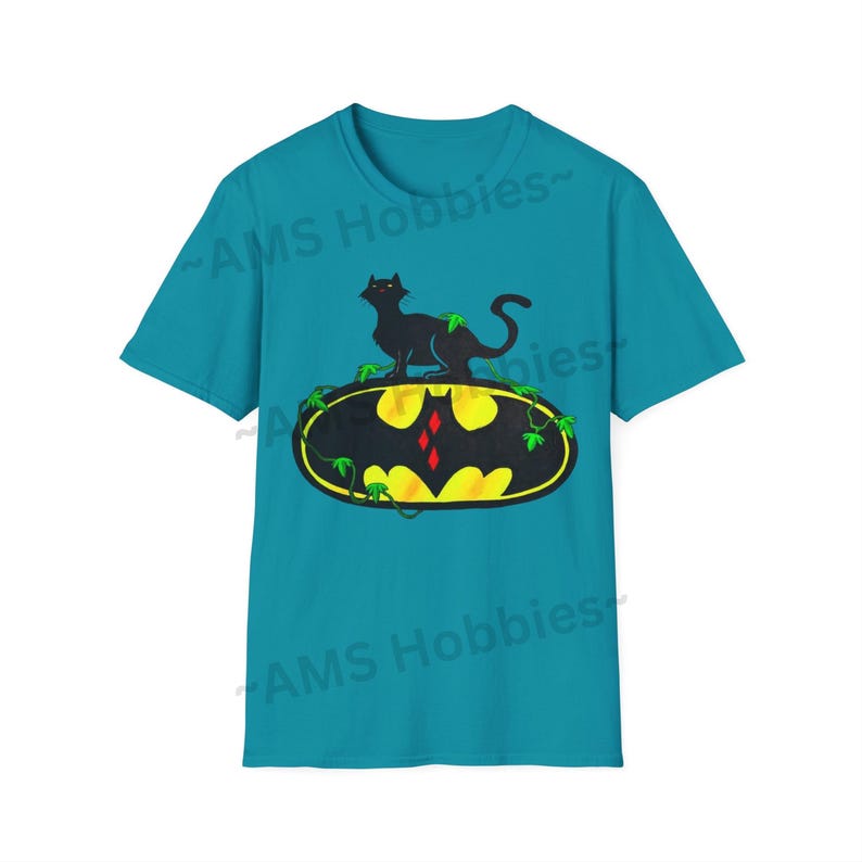 May include: A turquoise blue t-shirt with a black cat sitting on top of a yellow Batman logo with green vines. The text "AMS Hobbies" is printed on the shirt.