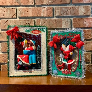 Op de afbeelding: Twee vintage kerstboomversieringen met een stel in een sneeuwsc&egrave;ne. De versieringen zijn ingelijst met groene en zilveren glitter met rode strikken. De tekst op de versieringen luidt "Shiny Brite" en "Merry Star".