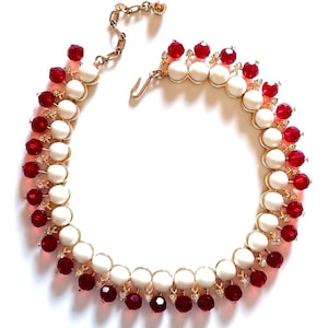 Op de afbeelding: Een vintage ketting met afwisselend witte en rode kralen, een goudkleurige ketting en sluiting. De ketting heeft een gelaagd ontwerp met kleine, heldere accentstenen. De rode kralen zijn facetgeslepen en de witte kralen zijn rond.