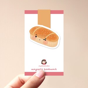 Op de afbeelding: Een schattig cartoon brood met een glimlach, een magnetische bladwijzer met de tekst "raychoostudios magnetic bookmark".