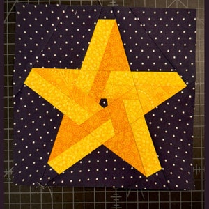 May include: A yellow star-shaped quilt block with a swirling pattern on a dark blue background with white polka dots.