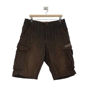 May include: Brown striped cargo shorts with a Volcom logo on the right pocket.