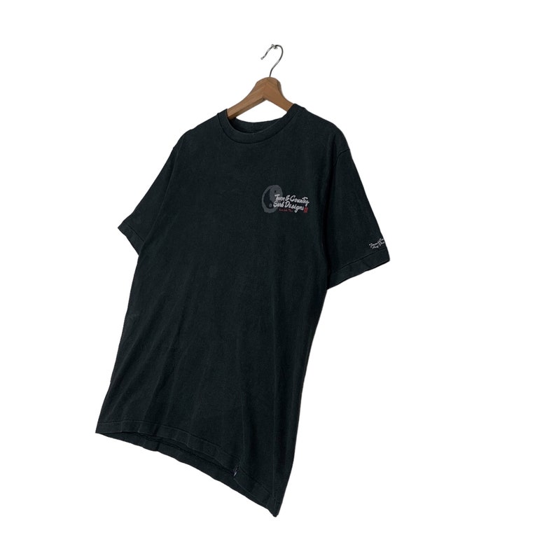 May include: Black short-sleeved t-shirt with a graphic of a yin-yang symbol and the text "Twin County Surf Designs".