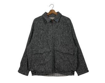 May include: A gray tweed jacket with a zipper closure and two pockets. The jacket has a black and white plaid lining.