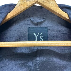 Puede incluir: Una chaqueta azul oscuro con una etiqueta negra que dice "Y's" en la parte posterior.