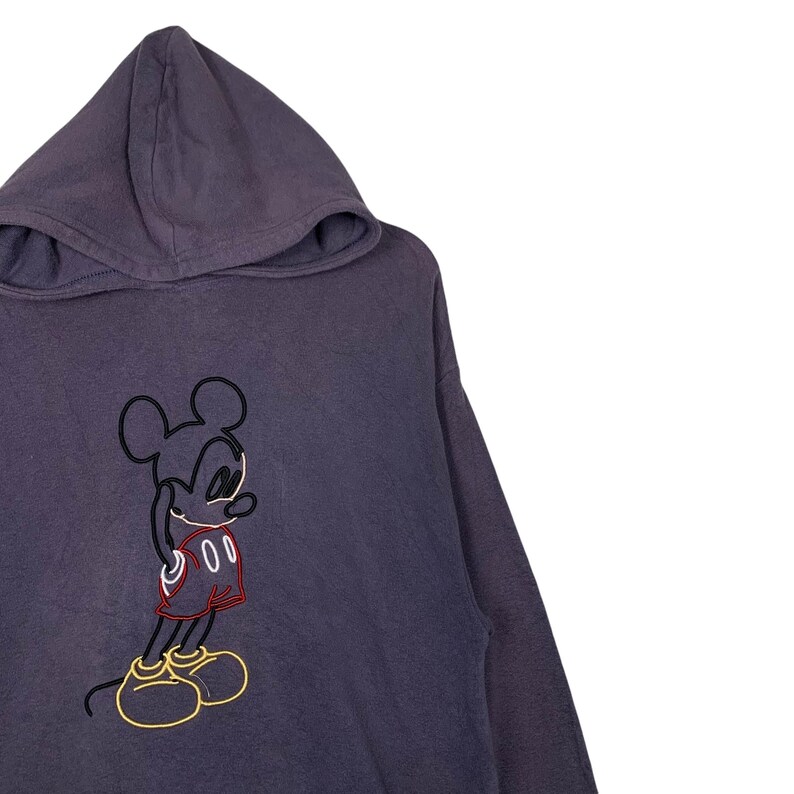 May include: A purple hooded sweatshirt with a black and white outline of Mickey Mouse wearing red shorts. The outline of Mickey Mouse is filled in with red and yellow.