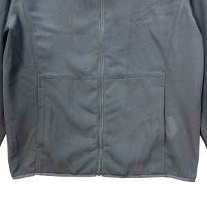 May include: A black zippered jacket with a pocket on the left side. The jacket has a ribbed hem and cuffs.