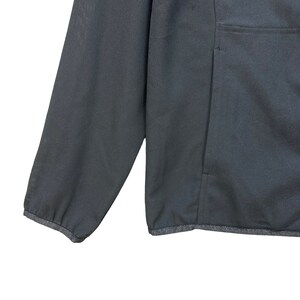 May include: A black zip-up jacket with a single pocket on the right side. The jacket has a ribbed hem and cuffs.
