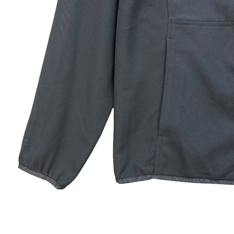 May include: A black zip-up jacket with a single pocket on the right side. The jacket has a ribbed hem and cuffs.