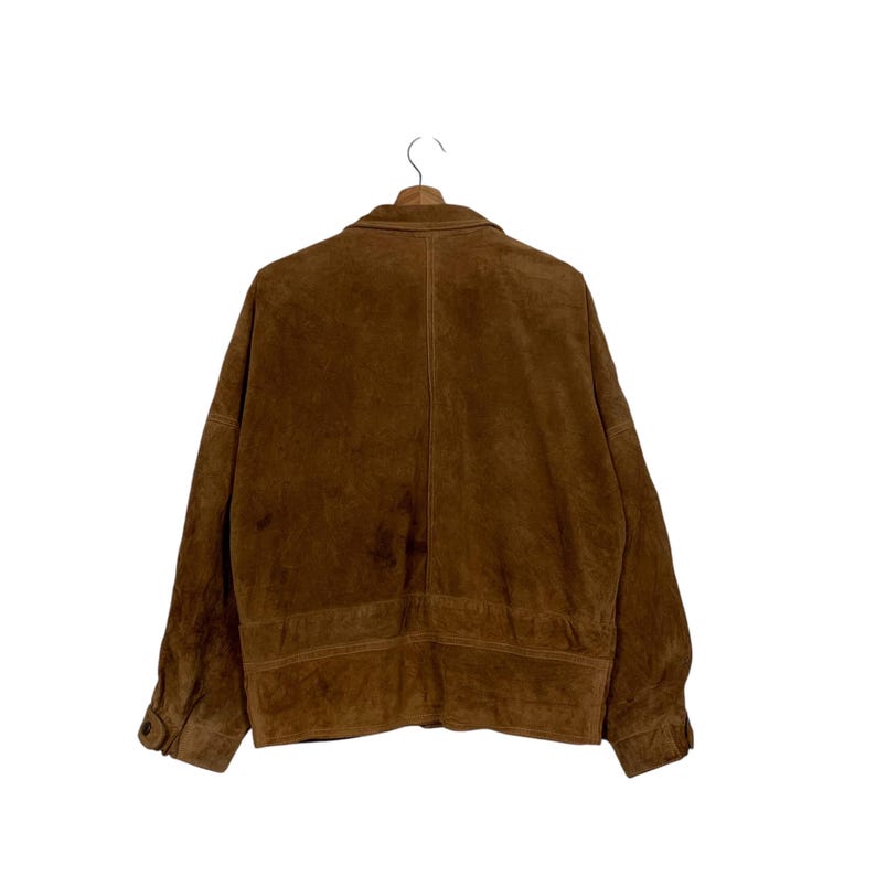 May include: A brown suede jacket with a button closure and a classic collar. The jacket is hanging on a wooden hanger against a white background. The back of the jacket is visible, showcasing the texture and color.