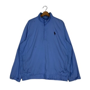 May include: A light blue windbreaker jacket with a black polo player logo on the left chest. The jacket has a snap button closure at the neck and a drawstring at the waist.