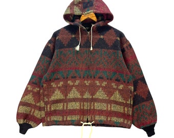 May include: A hooded jacket with a geometric pattern in shades of brown, green, and black. The jacket has a full zipper, drawstrings, and black cuffs. The hood is lined with a patterned fabric.