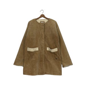 Puede incluir: Chaqueta de pana marrón claro con dos bolsillos delanteros y forro color crema. La chaqueta tiene cuello redondo y cierre de botones. Las mangas son largas y la chaqueta está colgada de una percha de madera.