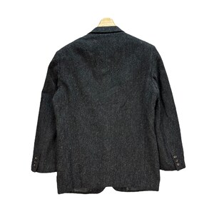 Puede incluir: Una chaqueta de tweed gris oscuro con cierre de un bot&oacute;n. La chaqueta tiene un corte cl&aacute;sico y una tela ligeramente texturizada.