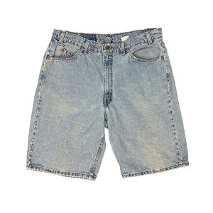 May include: Light blue denim shorts with a faded look. The shorts have five pockets and a button fly.