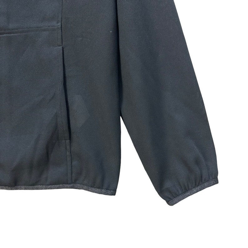 May include: A black long-sleeved jacket with a zipper closure and a pocket on the left side. The jacket has a ribbed hem and cuffs.