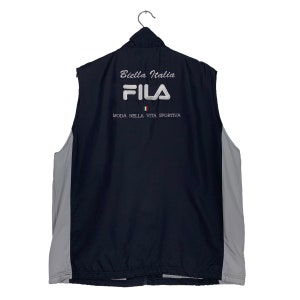 Puede incluir: Un chaleco Fila negro sin mangas con una cremallera blanca y un logotipo Fila blanco en la parte posterior. El chaleco tambi&eacute;n tiene el texto "Biella Italia" y "Moda Nella Vita Sportiva" en blanco. La bandera italiana tambi&eacute;n est&aacute; en la parte posterior del chaleco.