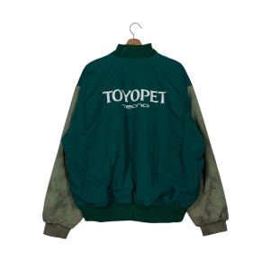 May include: A green and beige bomber jacket with the text "TOYOPET techno" on the back.