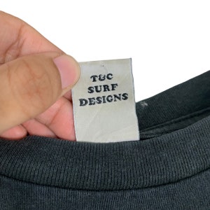 May include: A white tag with black text that reads "T&C Surf Designs".