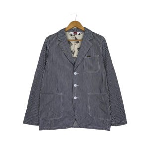 May include: A striped blue and white blazer with a button closure and two pockets. The blazer has a white lining with a pattern.