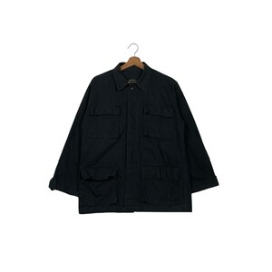 Puede incluir: Chaqueta negra con cuatro bolsillos delanteros y cuello. La chaqueta está colgada de una percha de madera sobre un fondo blanco. La chaqueta tiene mangas largas y cierre de botones.